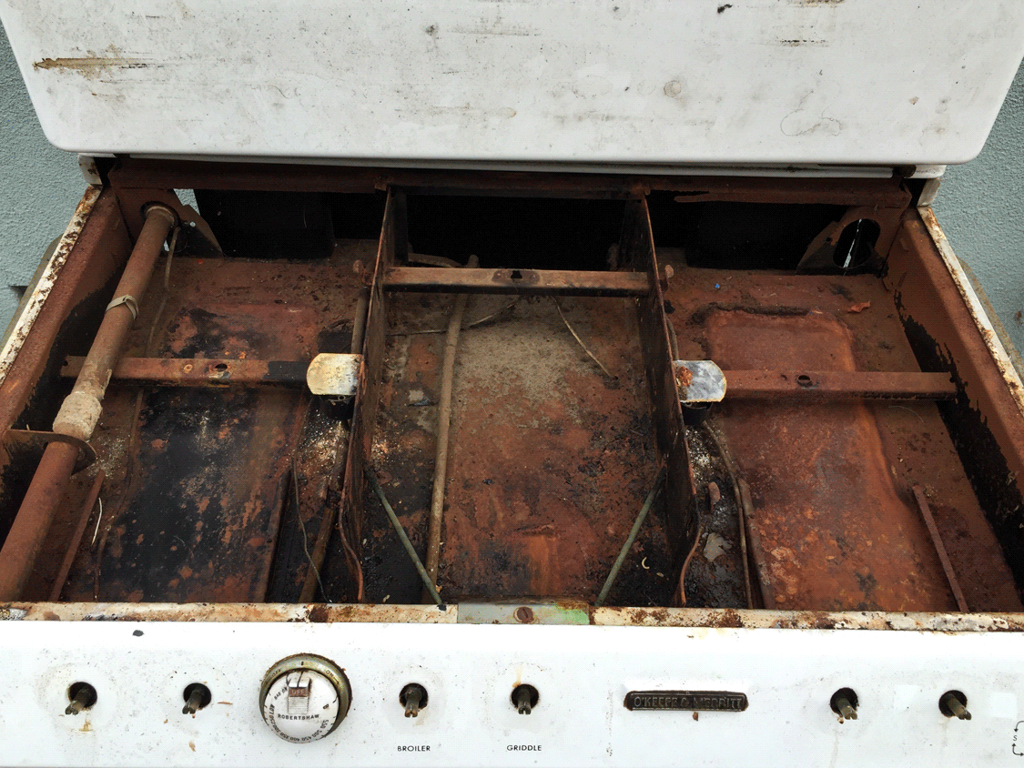 Stove top off revealing lots of rust.